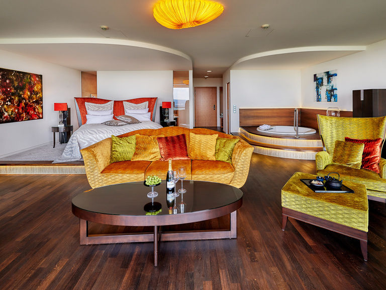 Luxus Suite mit Bett, bunter Couch und Whirlpool im Wellnesshotel Bayern